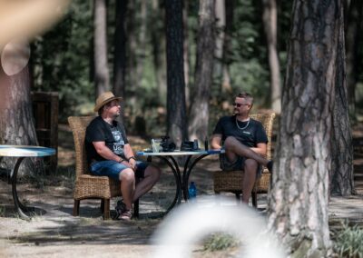 dva muži sedící u stolu v lese.
