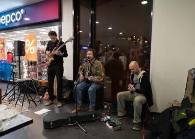 Skupina lidí hrajících hudbu před obchodem.